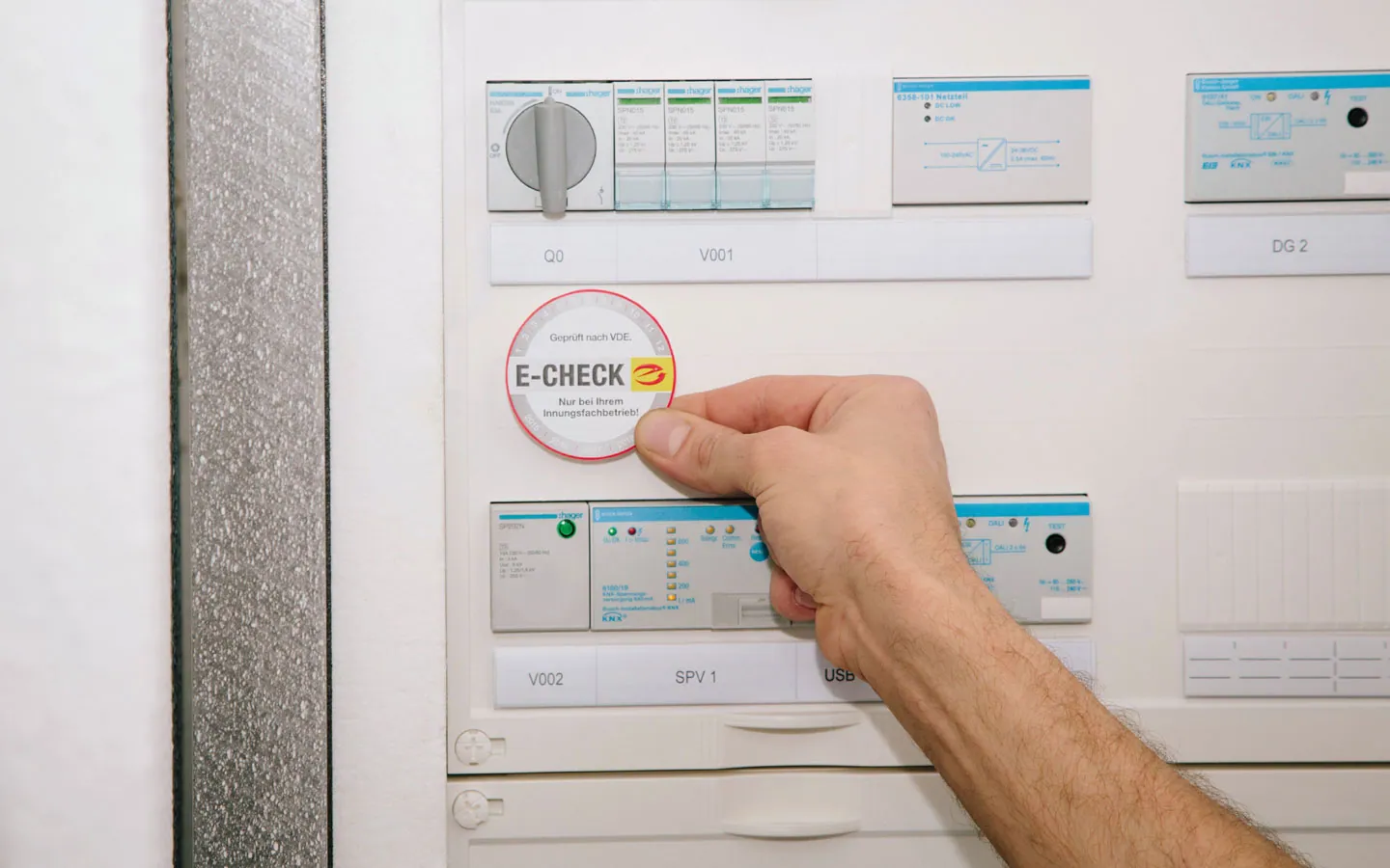 E-CHECK - Mitarbeiter klebt in der Verteilung die E-CHECK Plakette an · Elektro Roth