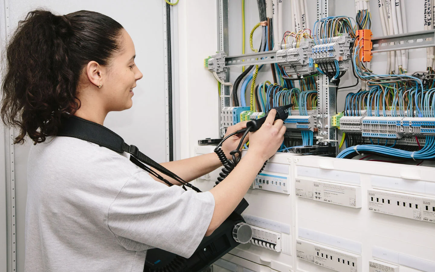 E-CHECK - Mitarbeiterin prüft im Schaltschrank mit einem Meßgerät · Elektro Roth
